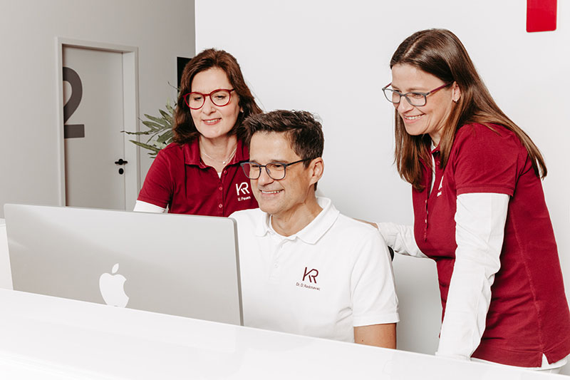 Dr. med. Dragan Radosavac mit Assistenz, Fachkräften am Schreibtisch, Blick auf Desktop